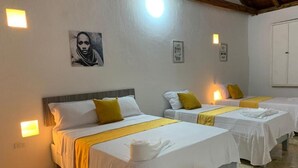 A hotel room with three beds, each with white bedding and yellow accents, and a painting on the wall. - Casa Gran Fuente (Cartagena)