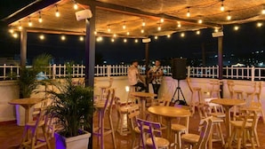 An outdoor seating area with tables and chairs, a thatched roof, and string lights. - Casa Gran Fuente (Cartagena)
