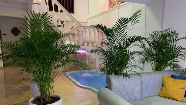 A modern indoor space with a white cushioned sofa, a small water feature, and potted plants. - Casa Gran Fuente (Cartagena)