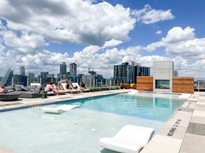 A rooftop pool with lounge chairs and a city skyline in the background. - 29th Floor Rainey St. Condo in Downtown Austin w/Rooftop Pool & Patio (Austin)