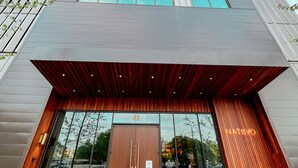 Een modern gebouw met een opvallende ingang, grote ramen en een houten gevel.