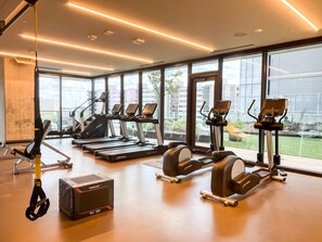 Une salle de sport moderne équipée de tapis de course, de vélos elliptiques et de matériel de musculation.