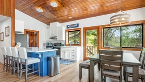 A modern kitchen with white cabinets, a blue island, and a stainless steel refrigerator. - Bass Lake House|Boat Slip|BBQ| Fire Pit |3/2 (Bass Lake)