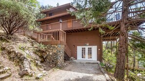 A two-story wooden cabin with a stone foundation, a wooden staircase, and a front door. - Bass Lake House|Boat Slip|BBQ| Fire Pit |3/2 (Bass Lake)