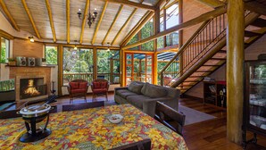 Un espacio habitable amplio con chimenea, asientos cómodos y una escalera que sube a un nivel superior.