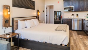 A modern hotel room with a large bed, a small desk, a built-in wardrobe, and a kitchenette with a microwave and refrigerator. - Best View Ever #17 at The Dwellings (La Verkin)