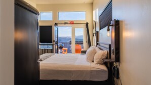A hotel room with a large bed, a view of the outdoors, and a balcony with chairs. - Best View Ever #17 at The Dwellings (La Verkin)