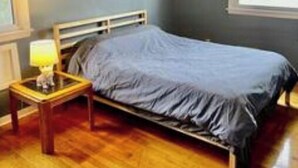 A bedroom with a bed, a nightstand with a lamp, a ceiling fan, and a window.