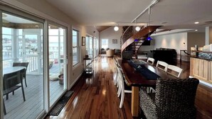 Un amplio salón con piso de madera, una mesa de comedor y una escalera que sube a un nivel superior.