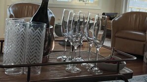 Una mesa con una botella de champán, varios vasos y una bandeja.