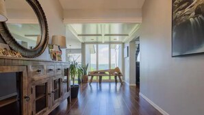 A hallway with a wooden cabinet, a mirror, and a bench.