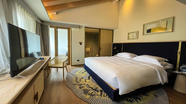 A hotel room with a large bed, a desk with a chair, a television, and a bathroom visible through an open door. - voco Nanjing Garden Expo by IHG (Nanjing)