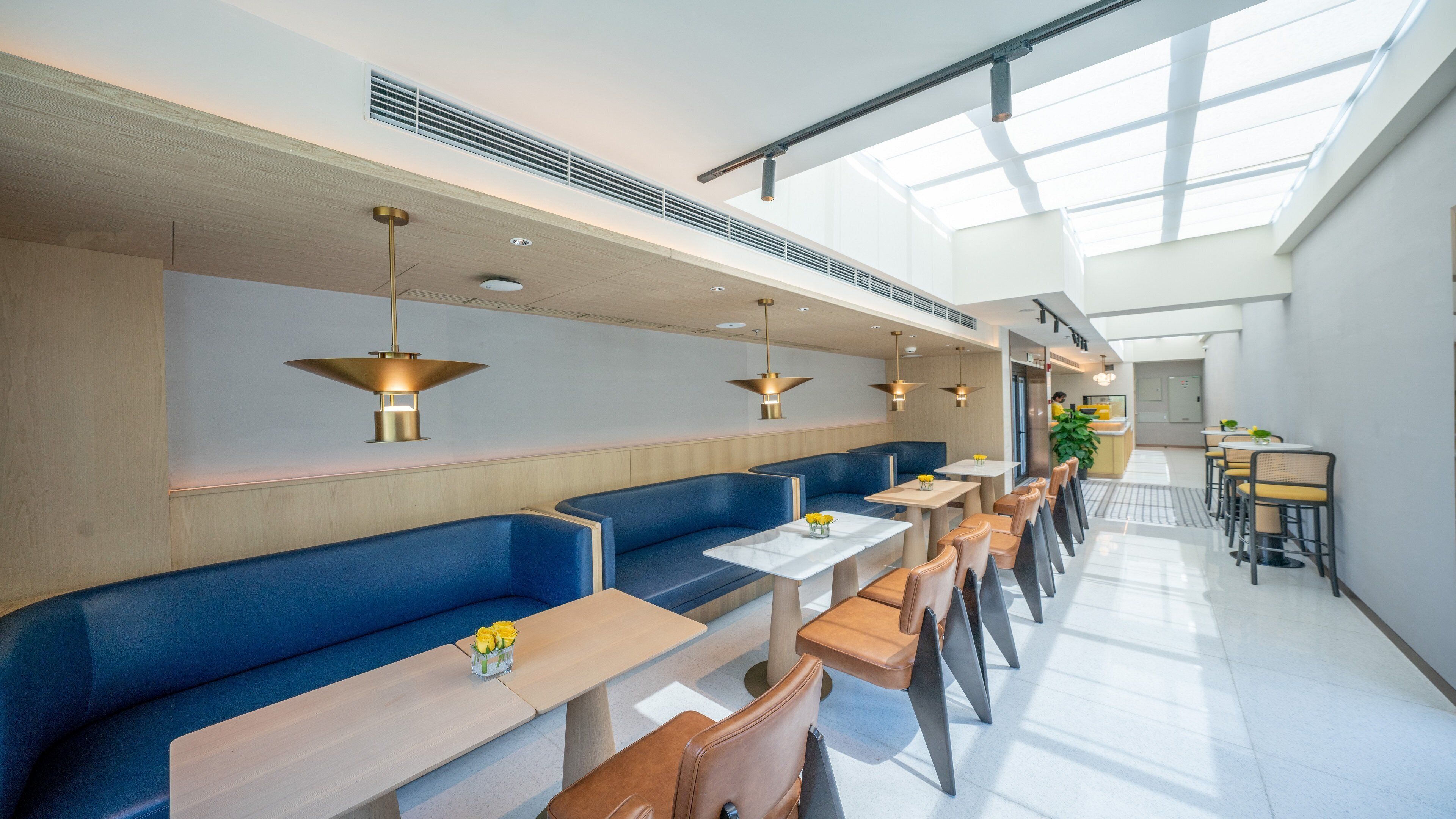 A modern restaurant with blue booths, wooden tables, and pendant lighting.