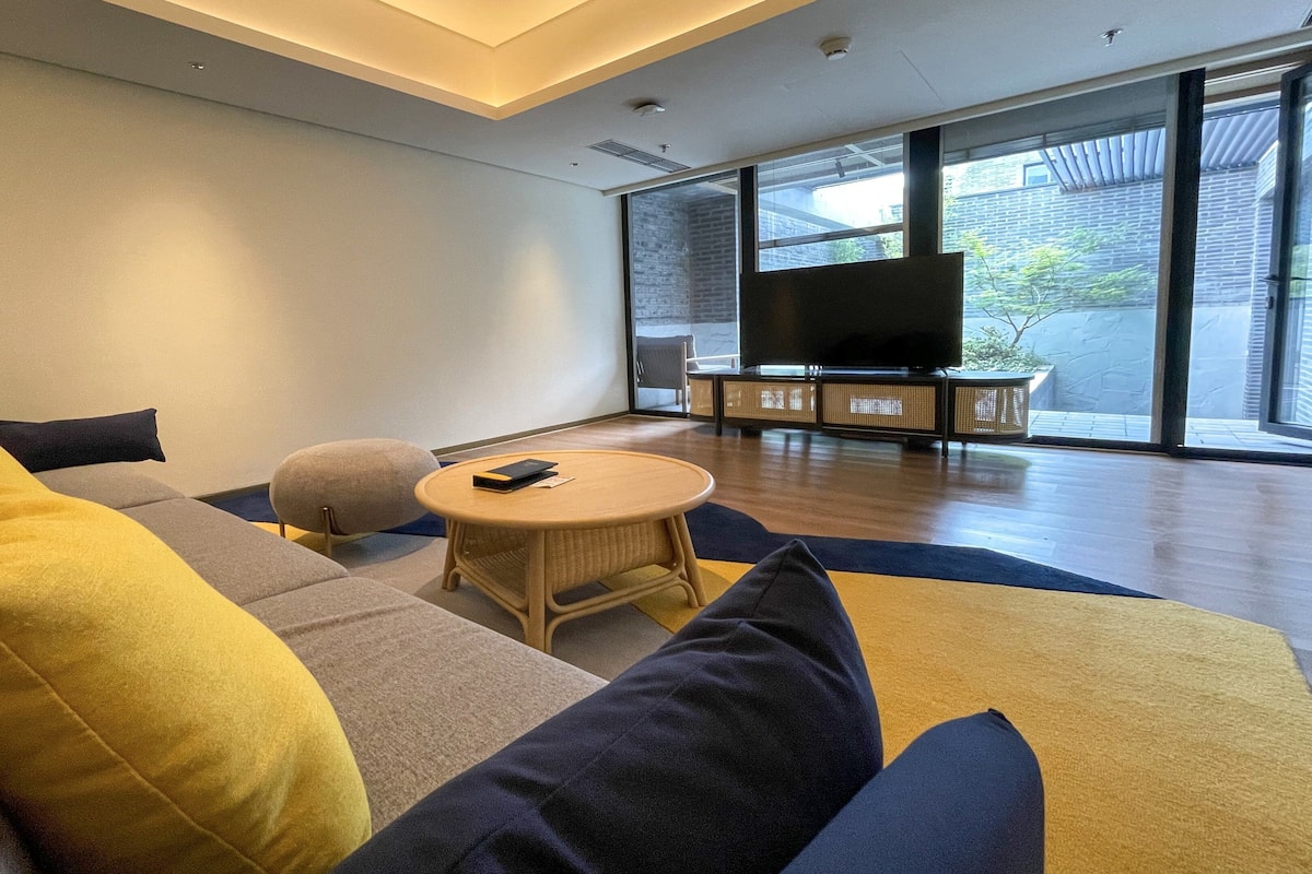 Un salon moderne avec un grand canapé d’angle, une table basse ronde et un téléviseur à écran plat.
