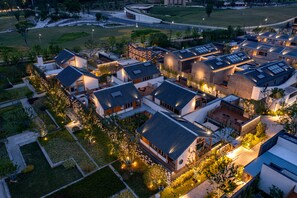 An aerial view of a modern residential area with multiple buildings, well-maintained lawns, and a curved road in the background. - voco Nanjing Garden Expo by IHG (Nanjing)