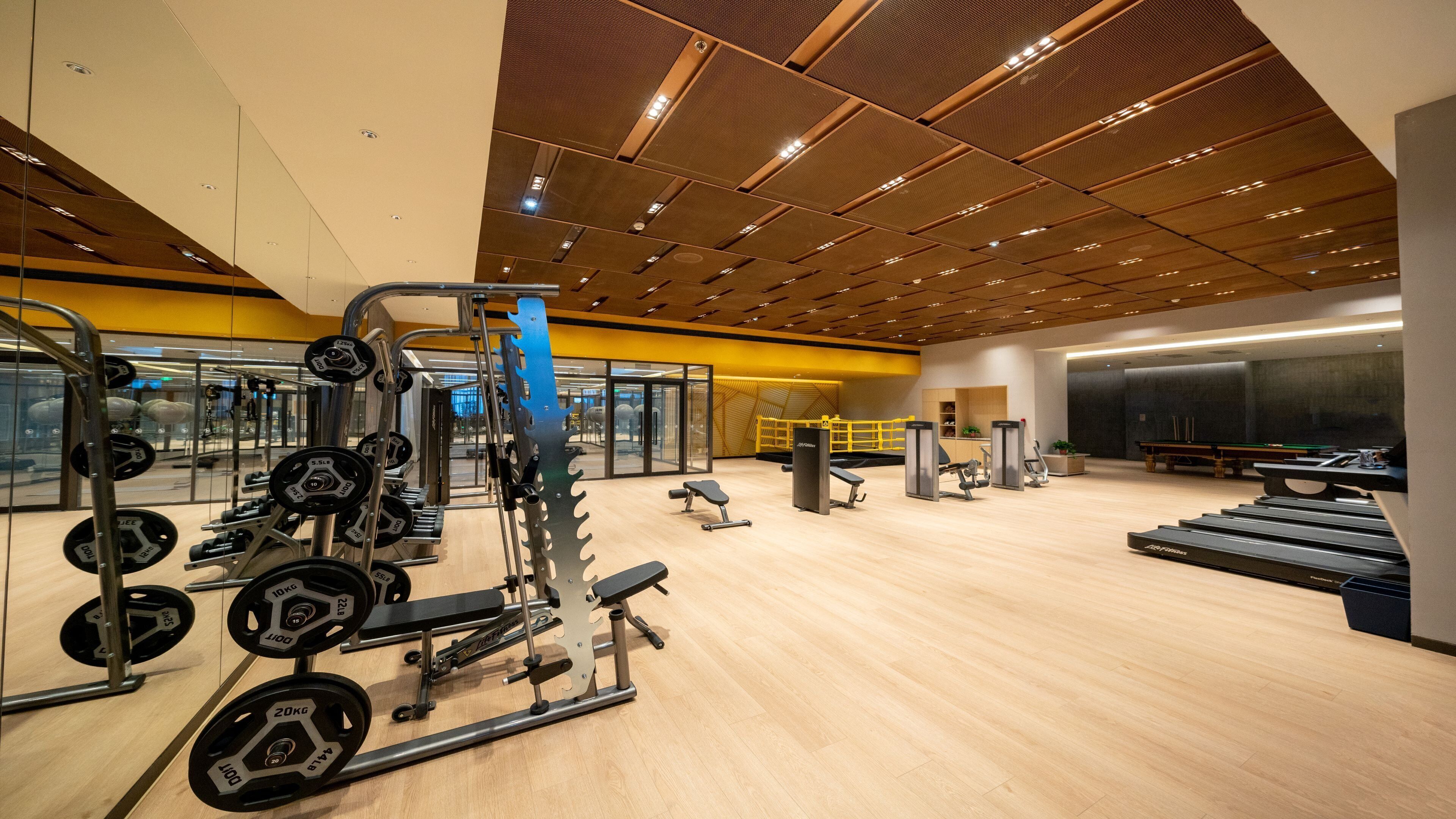 Ein modernes Fitnessstudio mit Krafttrainingsgeräten, Cardiogeräten und einem Billardtisch.