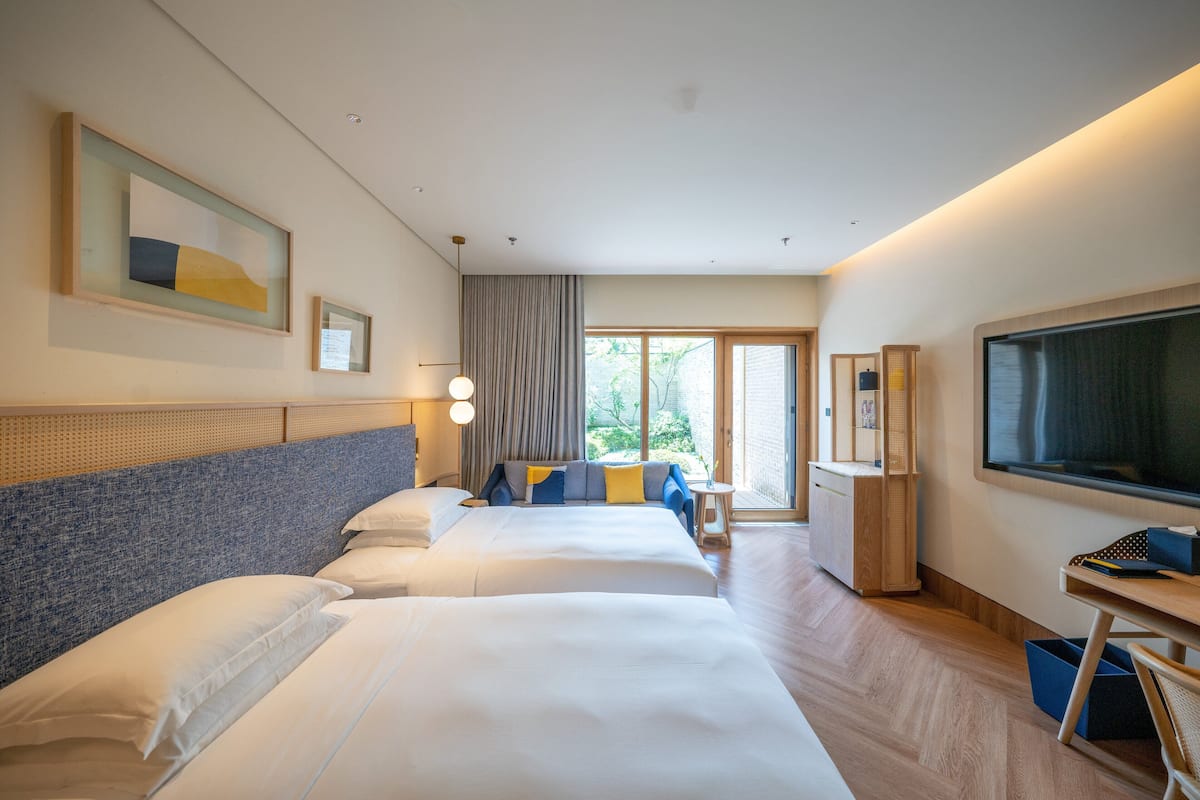 Une chambre d’hôtel avec deux lits, un bureau, une télévision et une vue sur l’extérieur.