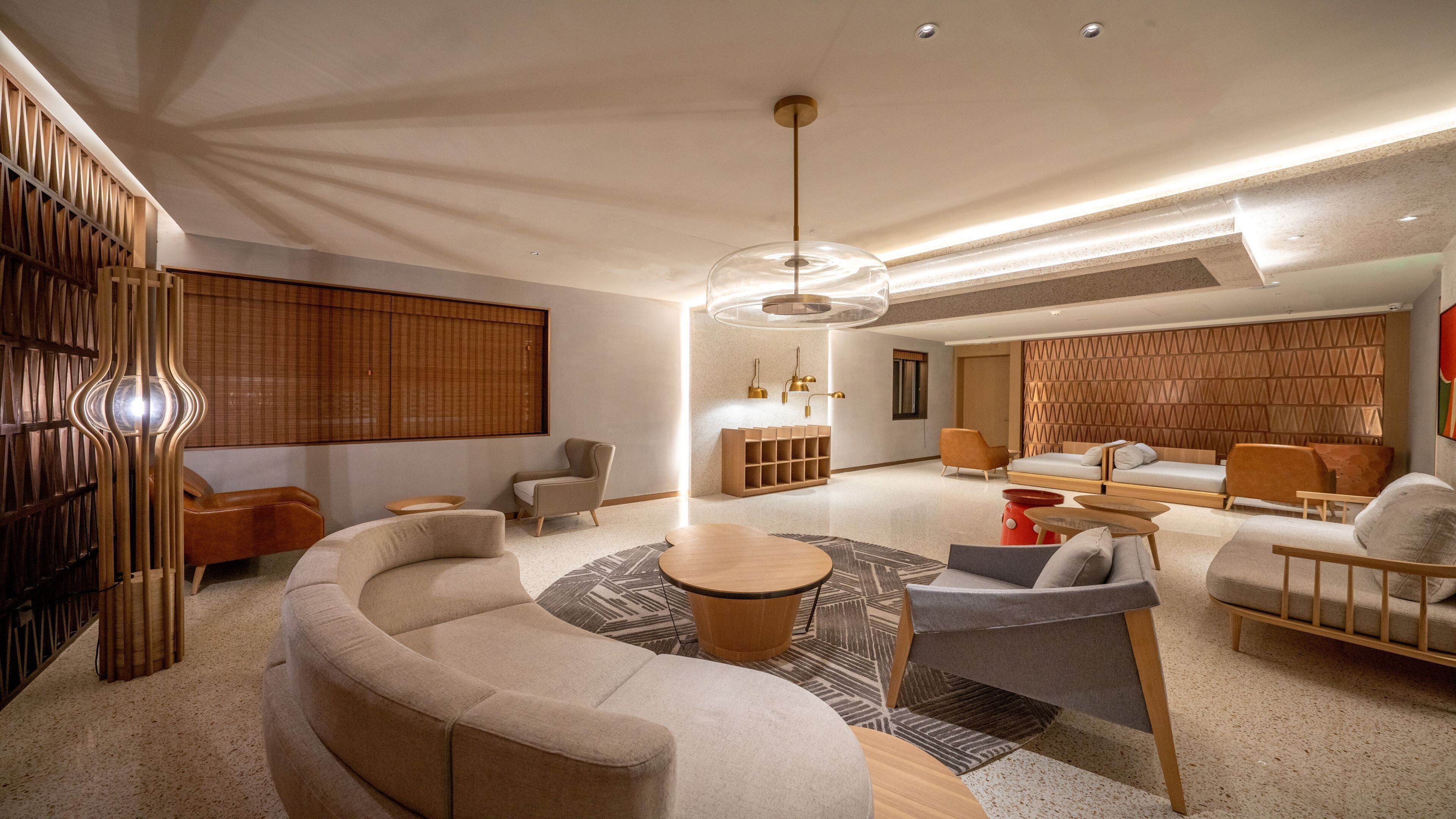 Una sala de estar moderna con un sofá curvo, una mesa de centro y un comedor con una mesa de madera y sillas.