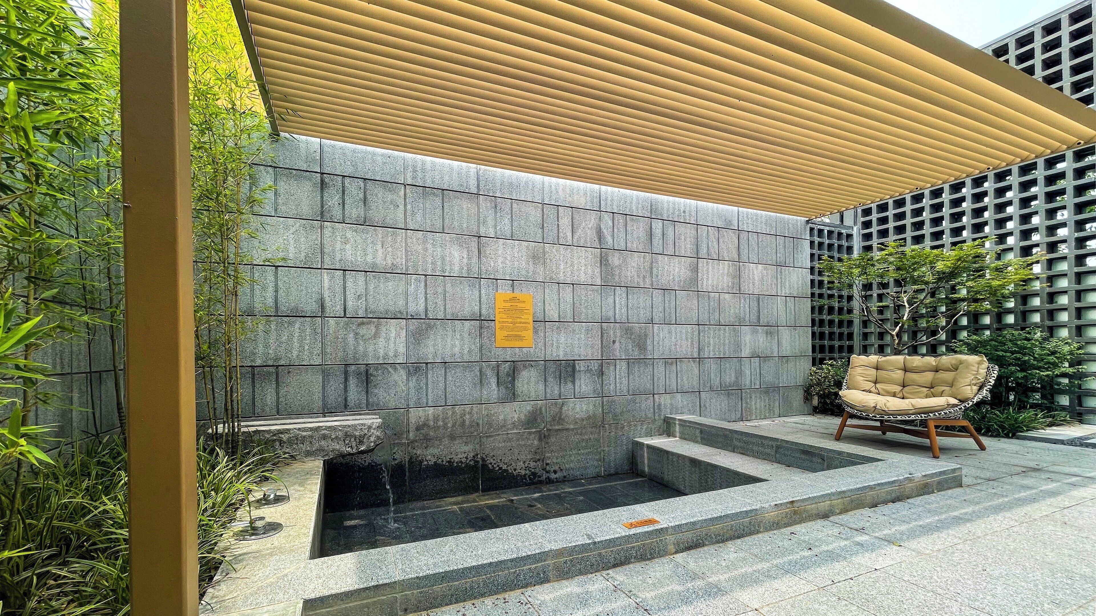 A stone wall with a water feature and a chair.