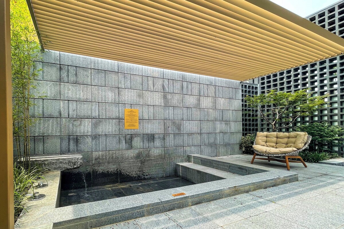 Un mur de pierre agrémenté d’un élément décoratif à base d’eau et d’une chaise.