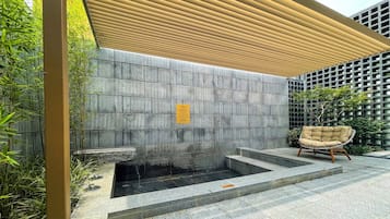 A stone wall with a water feature and a chair.