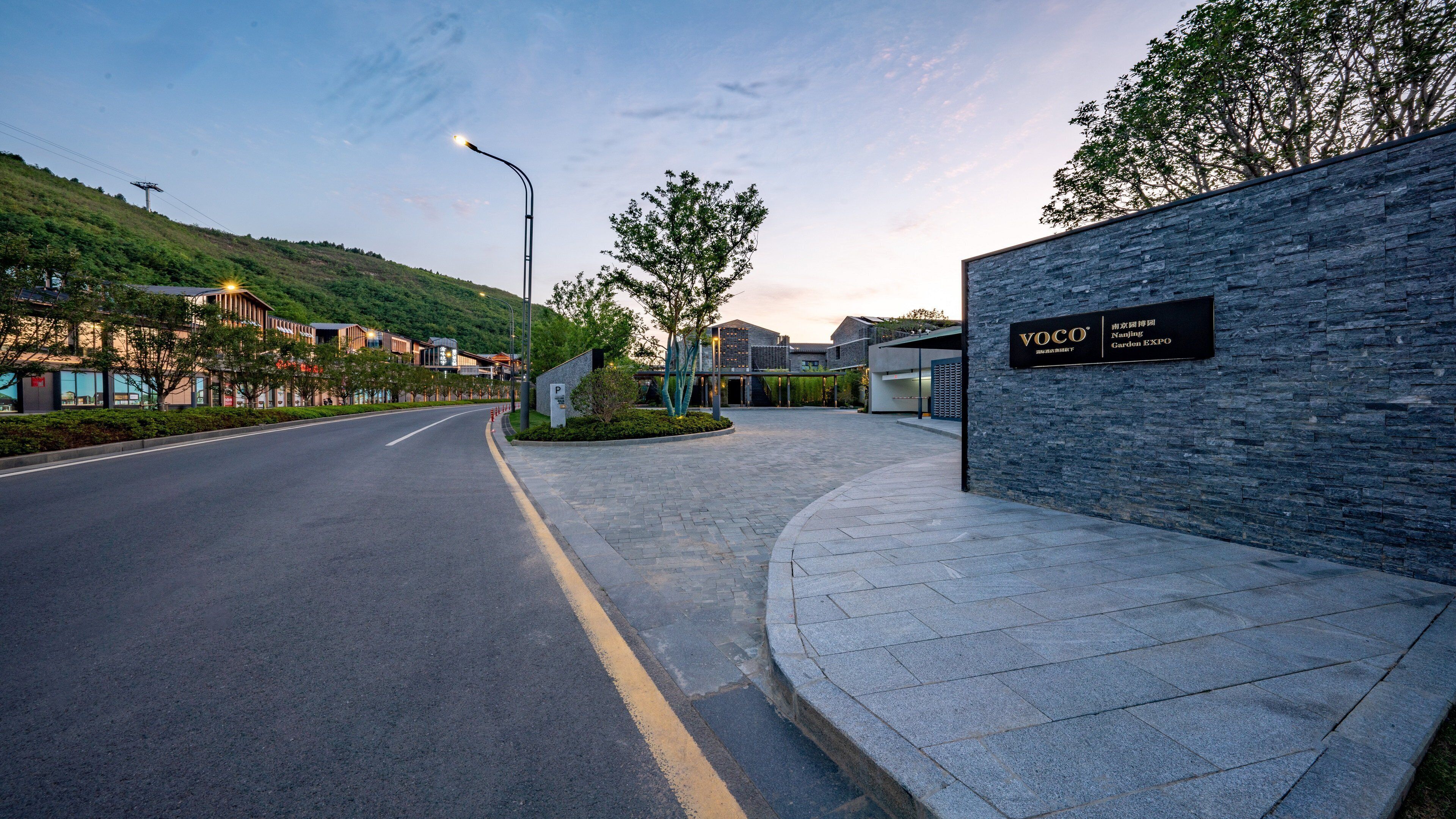 A modern building with a stone facade and a sign for "VOCO Nanjing Garden EXP."