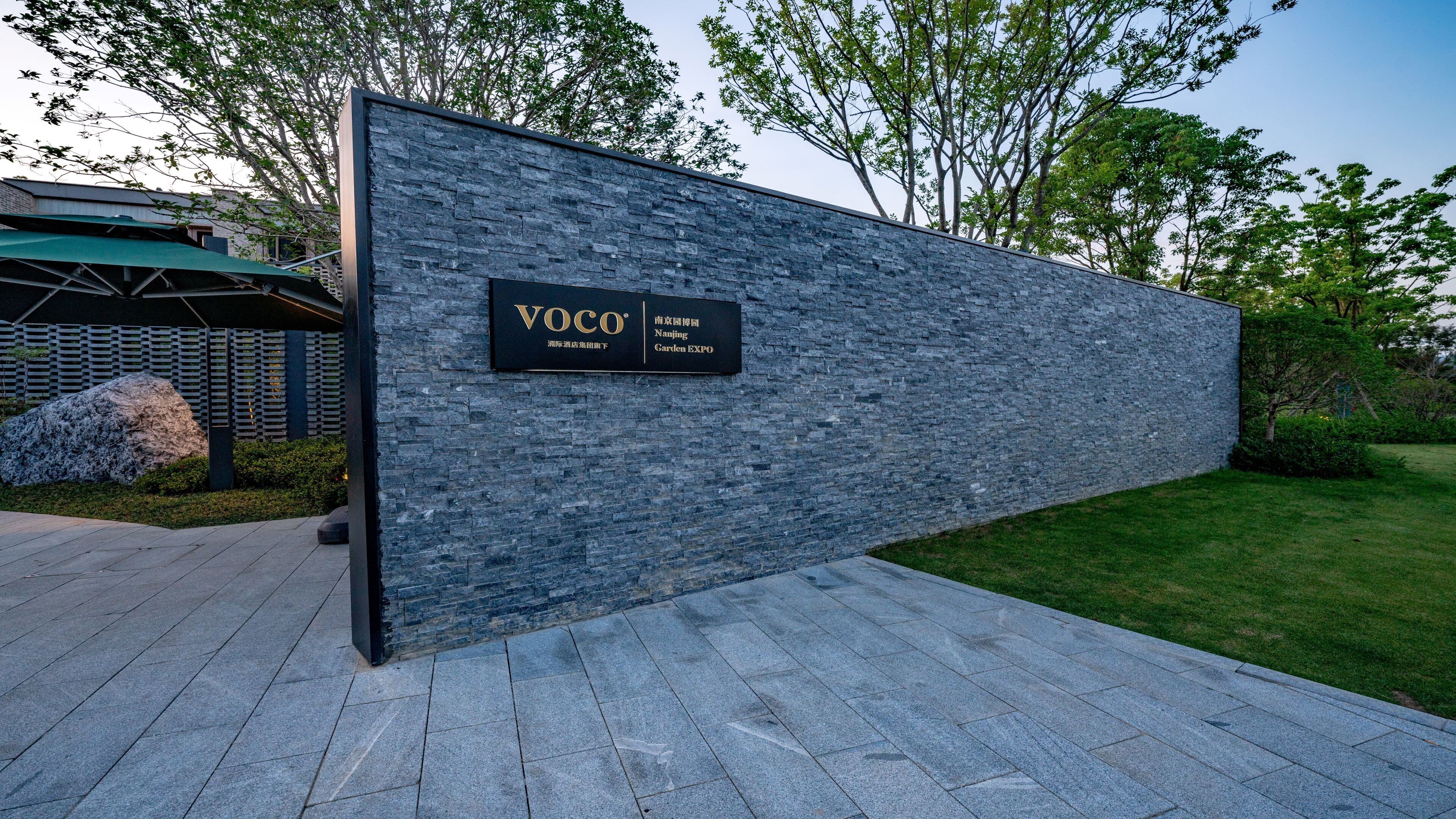 Un edificio moderno con fachada de piedra y un cartel que indica que es el Voco Garden Expo.