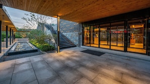 A modern building with a stone facade, a wooden staircase, and a glass entrance.