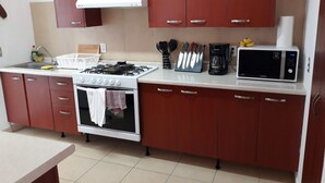 Cozinha equipada com fogão, forno, micro-ondas e utensílios diversos.