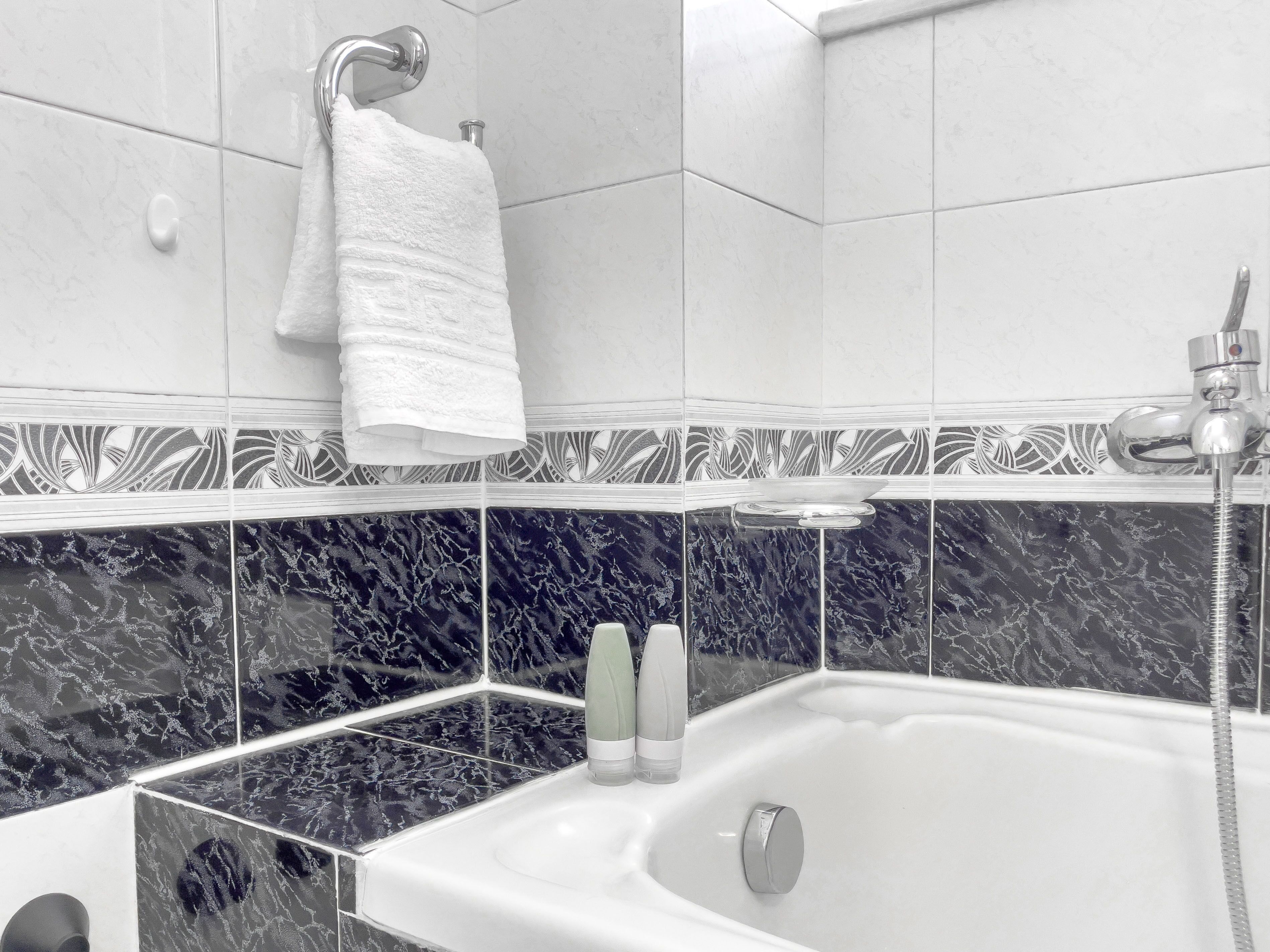 A modern bathroom with a white bathtub, a shower, and a towel rack.