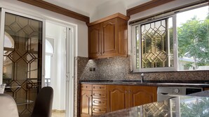 A kitchen with wooden cabinets, a granite countertop, and a window with a geometric pattern.