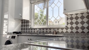 A kitchen with a window, a washing machine, and a sink.
