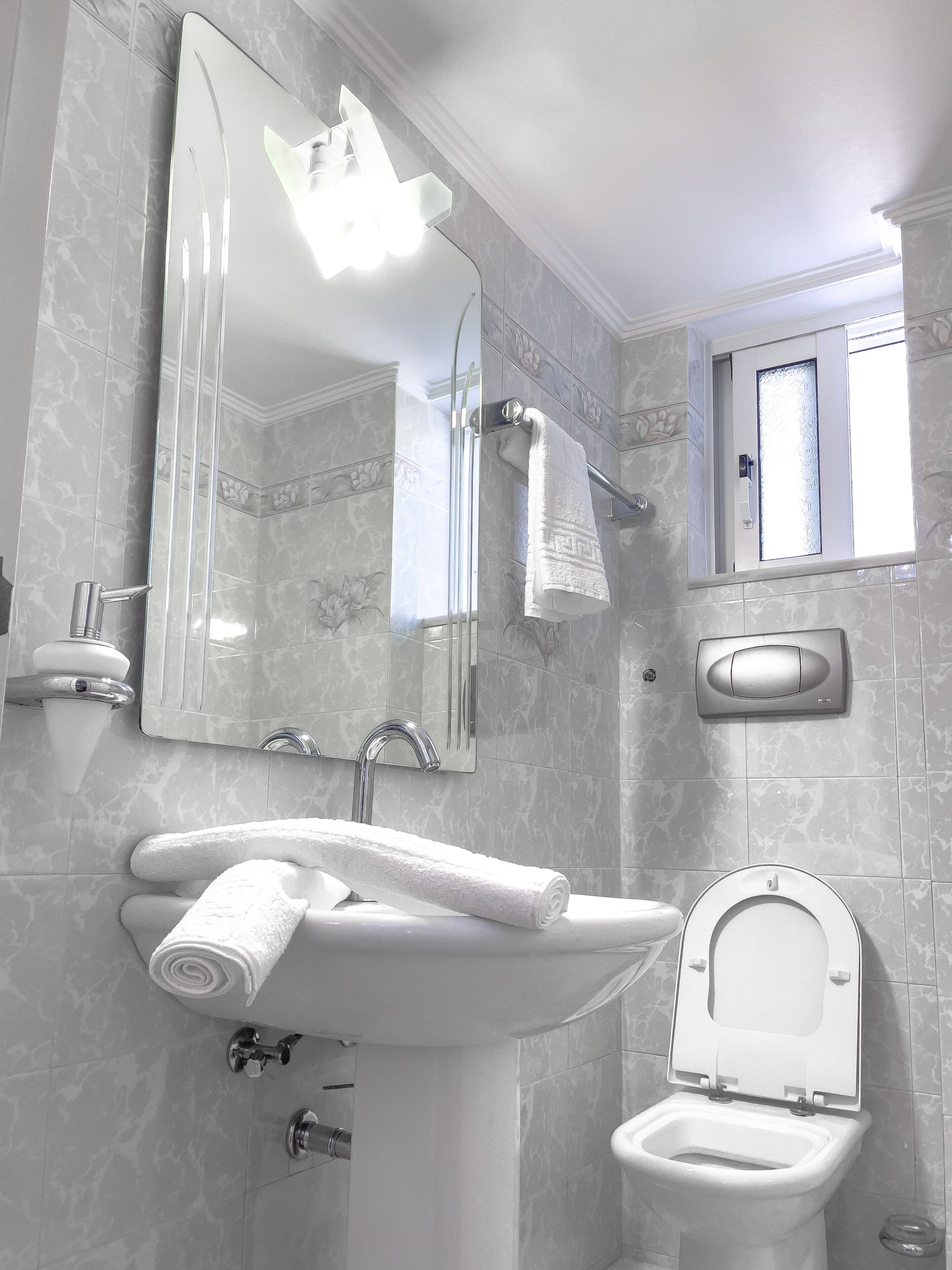 Ein Badezimmer mit Waschbecken, Spiegel, Toilette und Fenster.