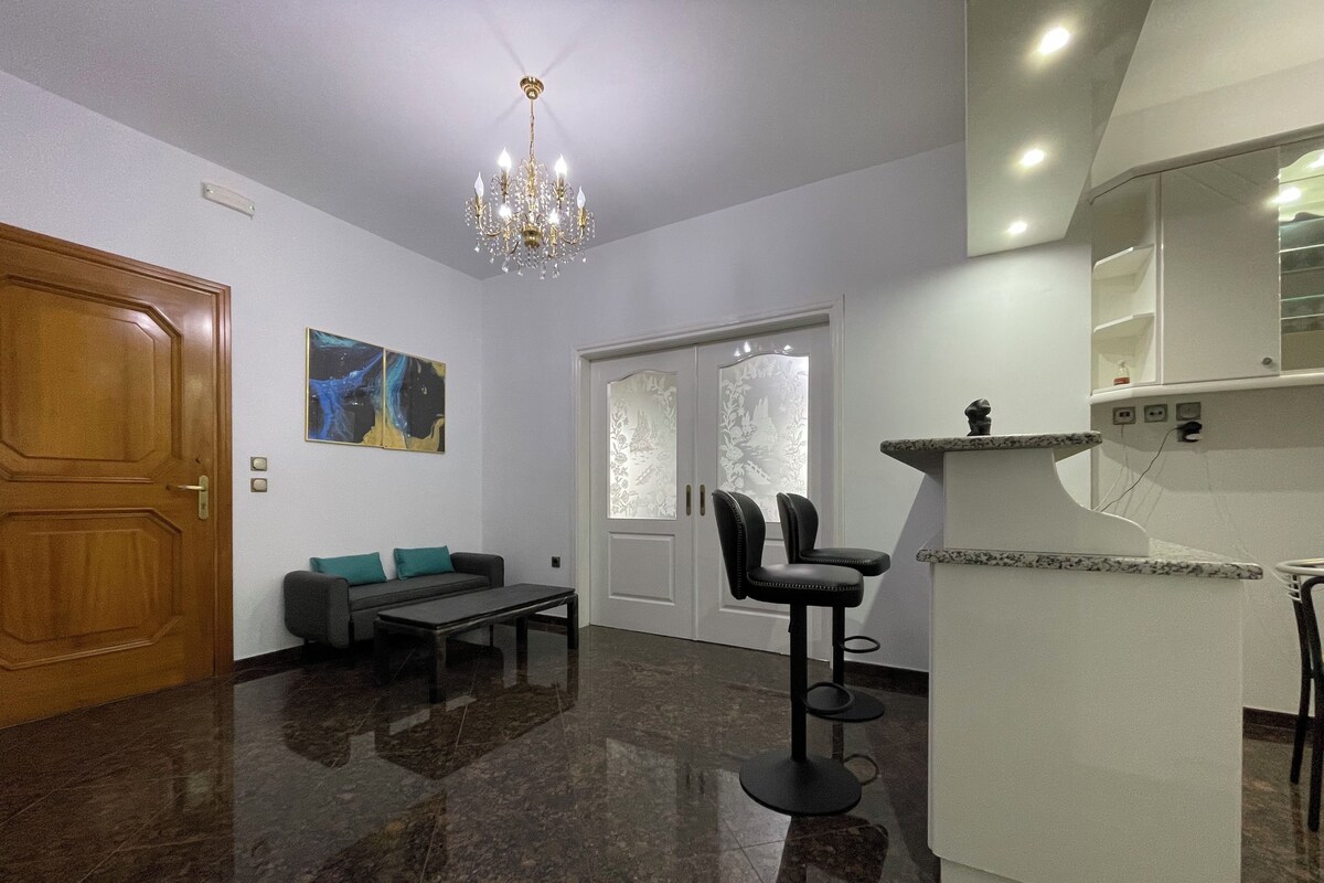 Un intérieur moderne agrémenté d’un lustre, d’un canapé, d’une table à manger et d’un coin cuisine.