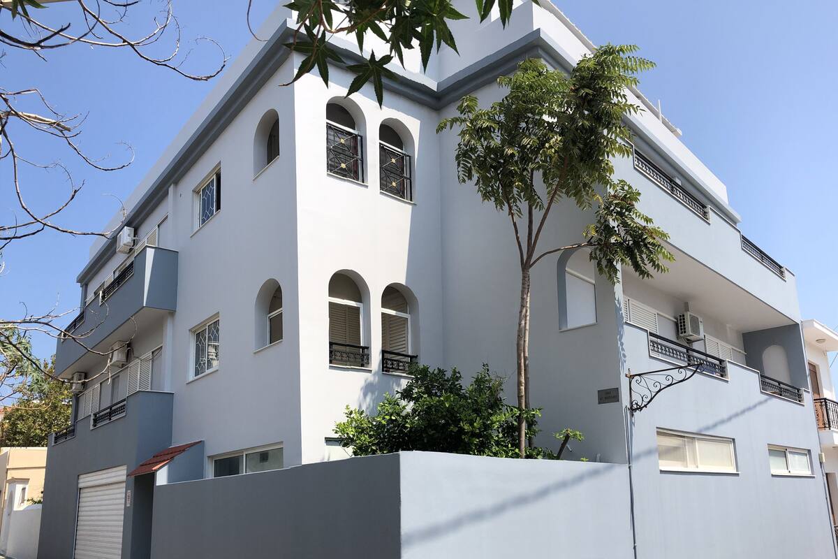 A modern two-story building with a white facade, multiple windows, and balconies.