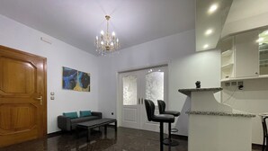 A modern living room with a chandelier, a sofa, a coffee table, and a dining area with a bar counter.