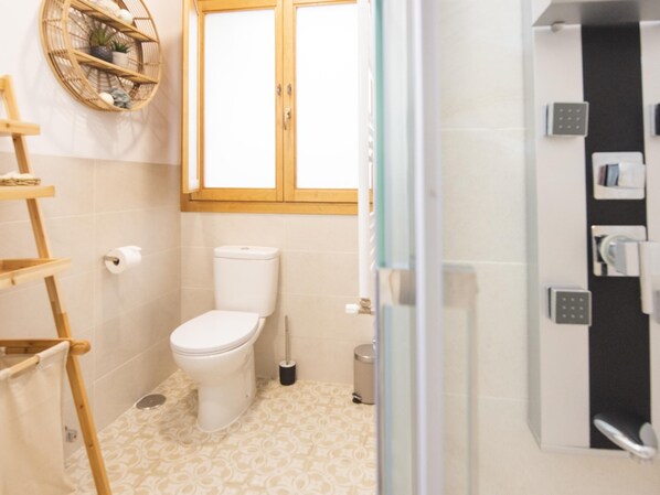 A bathroom with a toilet, a bidet, a trash bin, and a shower area. - La Quinta Calle (Toledo)