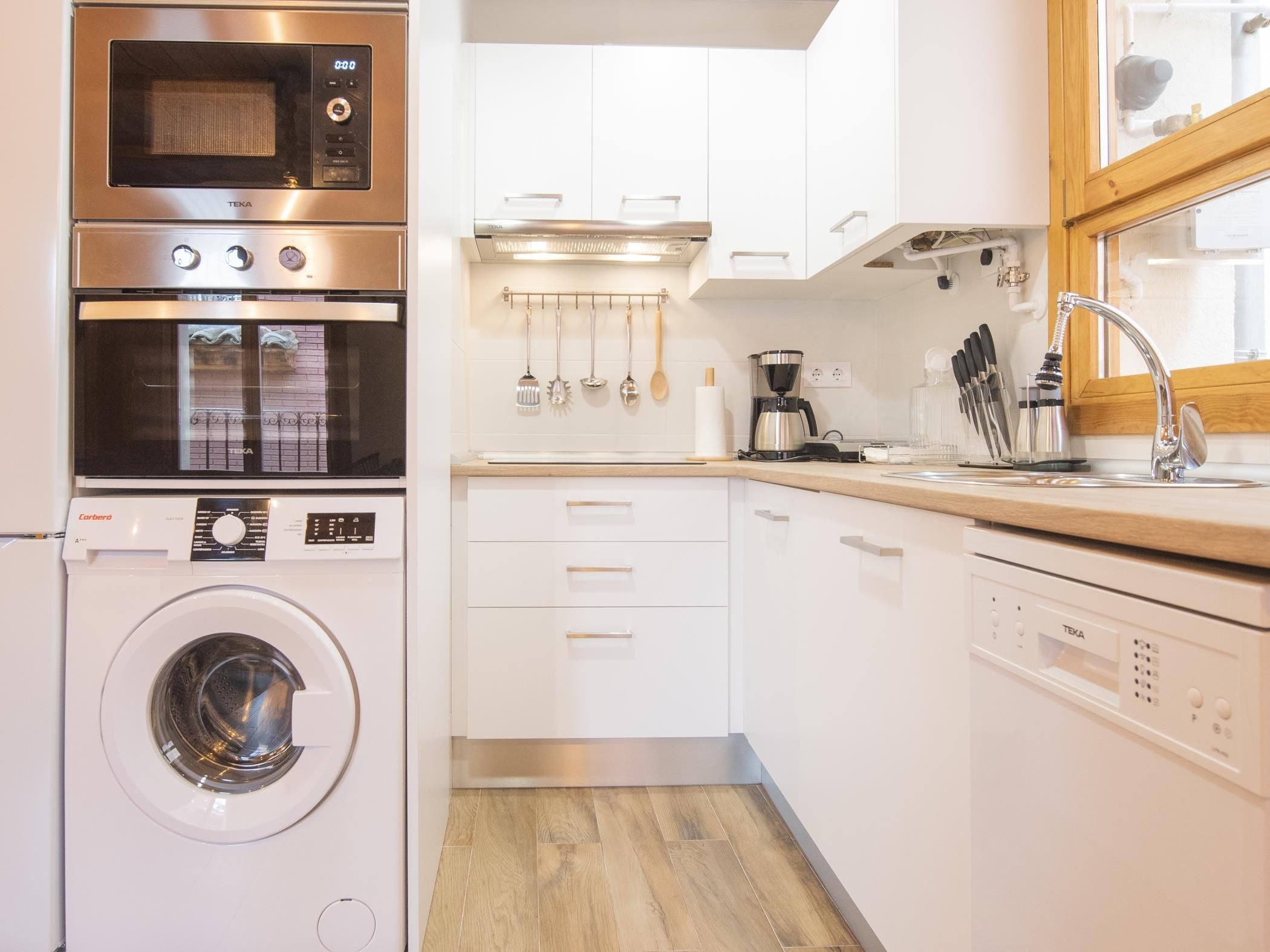 Una cocina compacta equipada con lavadora, cafetera y lavavajillas.