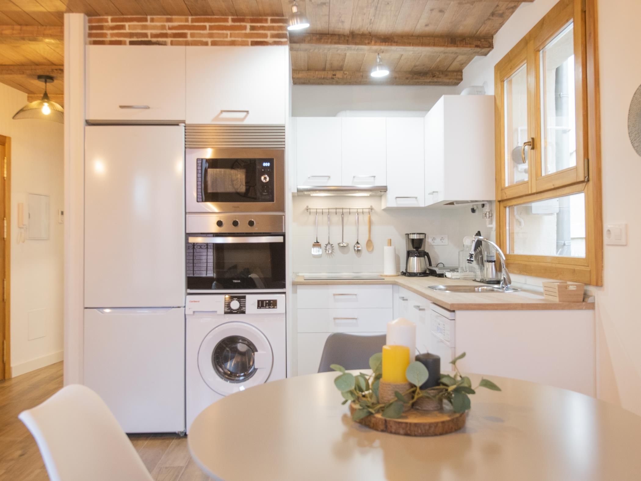 Cocina compacta con refrigerador, microondas, horno y lavadora.