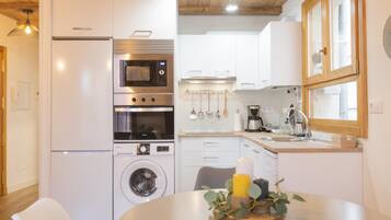 Cocina compacta con refrigerador, microondas, horno y lavadora.