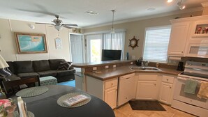 A compact kitchen with white cabinets, a black countertop, and a dining area with a round table and chairs. - Relaxing  Home in gated community (Cudjoe Key)