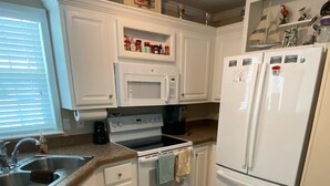 A kitchen with white cabinets, a double oven, a microwave, a sink, and a refrigerator. - Relaxing  Home in gated community (Cudjoe Key)