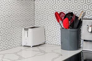 A kitchen with a toaster, a red spatula, and a whisk in a container.