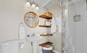 Un baño con lavamanos, espejo, toallero y ducha.