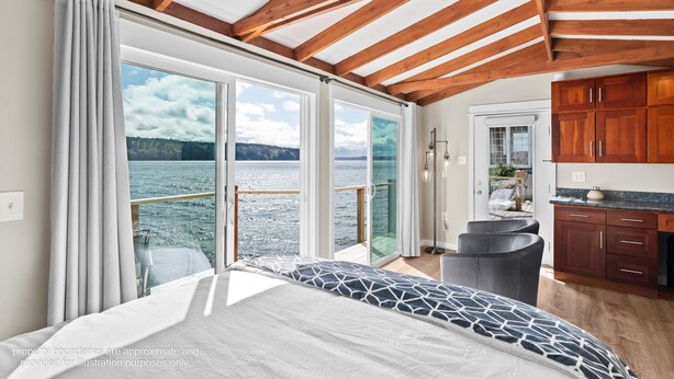 Ein Schlafzimmer mit einem großen Bett, Blick auf das Wasser und Holzbalken an der Decke.