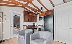 Cocina moderna con vigas de madera, refrigerador, estufa y sillas grises.