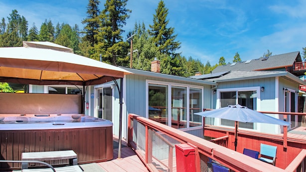 A hot tub, outdoor seating, and a deck with a railing.