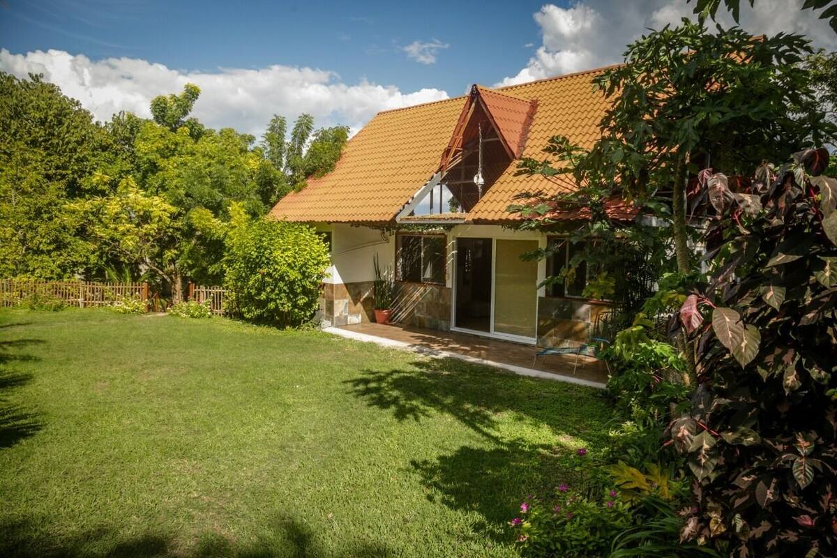 Ein Haus mit geneigtem Dach, einer Veranda und einem gepflegten Rasen.