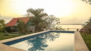 A rectangular swimming pool with a tiled edge, surrounded by a grassy area and a wooden deck. - Seven Blue House Village & Lodge (Bacalar)