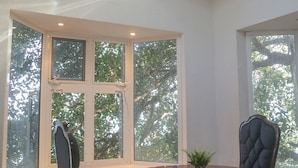 A dining area with a round table, two chairs, and a hanging light fixture. - Seven Blue House Village & Lodge (Bacalar)
